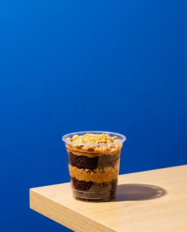 Bolo de pote sobre mesa de madeira com fundo azul vibrante